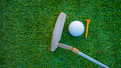 Golf clubs and golf balls on a green lawn in a beautiful golf course with morning sunshine.