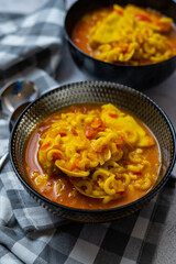 noodle and seafood casserole soup. two black bowls and neutral bottom.