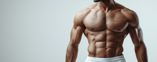 Fototapeta premium A fit male model showcasing a muscular physique with defined abs and toned arms.