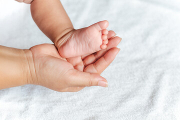 A baby's foot is held in a mother's hand. The baby is small and the mother is holding it gently.