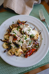 baked vegetables with sauce on a white plate on the table in a house