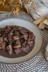 plate of meat with wine sauce on a wooden table in a house