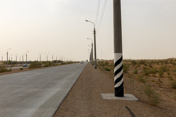 Stretching highway lined with electric poles under a clear sky in a desert landscape