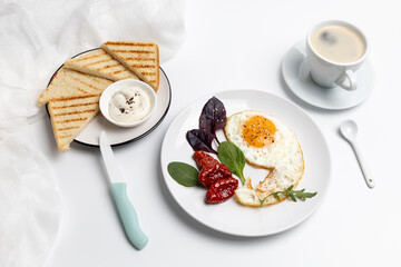 Fried egg on the plate, a cup of coffee and toasts with cheese sauce.