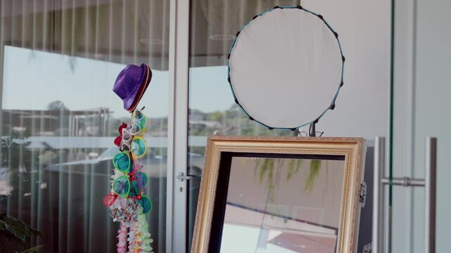 Photo booth setup with a decorative mirror, colorful props, and party accessories