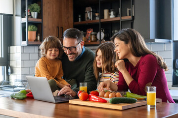 Happy parents at the kitchen counter with their children at home, enjoying weekend together