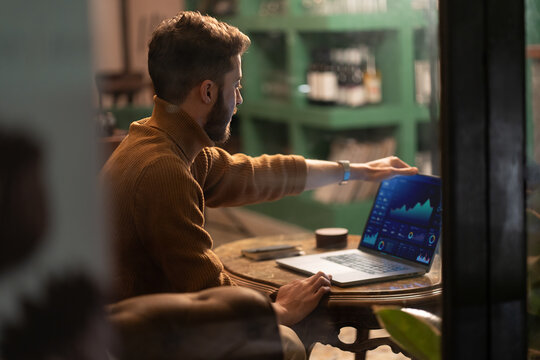 Remote worker using laptop for data analysis in trendy urban cafe - Powered by Adobe