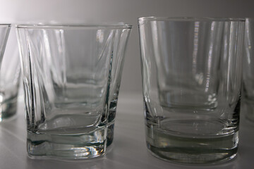 Empty glass glasses for water and alcohol stored in a dimly lit shelf.