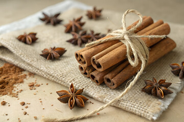 Fototapeta premium Cinnamon sticks arranged neatly with anise stars on a rustic surface