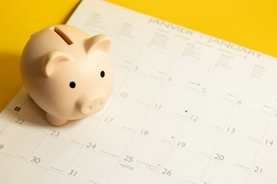 Top view of piggy bank on a calendar on a yellow isolated background, concept of saving in the year