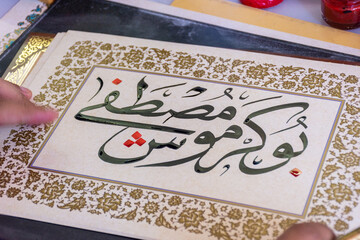 Close-up of a calligraphist writing an Arabic name for a customer in Arabic calligraphy with ink.