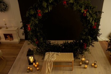 Cozy Christmas interior with a large wreath, candles, and festive decor on wooden flooring
