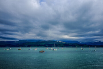 Obraz premium Boats at anchor on Menai Straits with moody sky