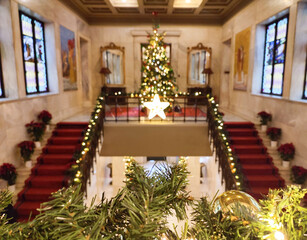 Photo of Athens City Hall adorned with festive Christmas decor, featuring lush green garlands, shimmering golden ornaments, and a blurred bokeh backdrop highlighting a beautifully lit Christmas tree.