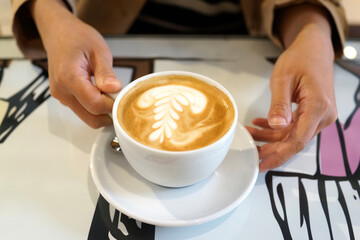 Hands Holding a Cup of Latte with Latte Art