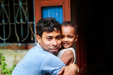 South asian young father hugging his son in outdoor, happy family photo, family togetherness concept 