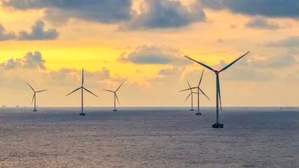 Tall windmill turbines against a clear blue sky, generating renewable energy in the serene Go Cong, Vietnam landscape by the sea. Like windmill park Westermeerdijk in the Noordoostpolder Netherlands