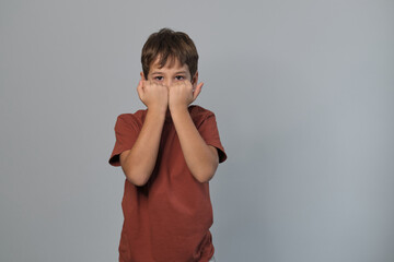 A boy brings his fists to his face, peering over them with a serious expression. This protective pose reflects the natural instincts of children to both engage and retreat, exploring boundaries.