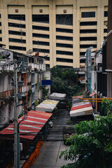 Small residential neighborhood in the center of Bangkok with some local businesses next to a skyscraper; contrasts between the wealthy and the poorer people; Thailand