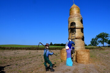 A view of a decoration situated on a field or meadow made out of dry hay bales, crops, and grass...
