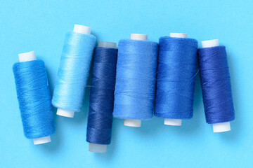 Blue thread spools background with copy space for text close-up flat lay top view