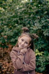 cute little girl in the autumn forest in a brown sweater