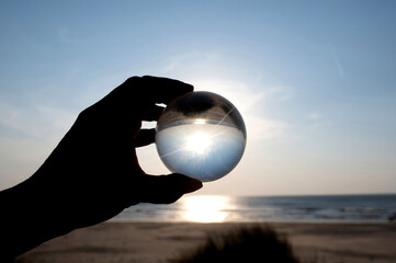 Beach and sea reflected in a ball in a human hand