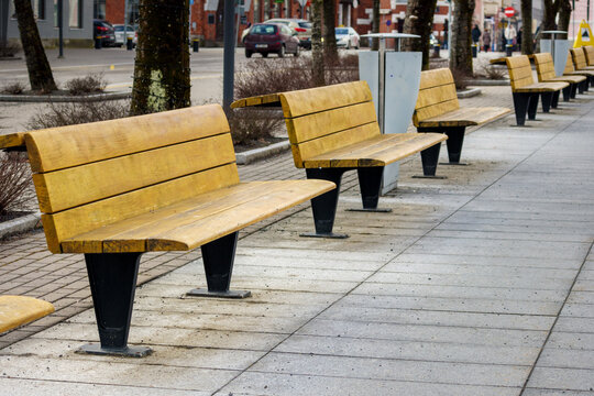 
A wooden bench in the park on the side of the sidewalk