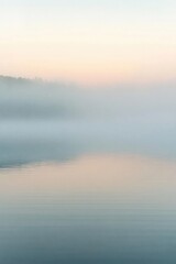 A serene landscape with fog over calm water at dawn.