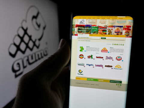 Stuttgart, Germany - 11-08-2024: Person holding cellphone with webpage of Mexican food processing company Gruma S.A.B. de C.V. on screen with logo. Focus on center of phone display.
