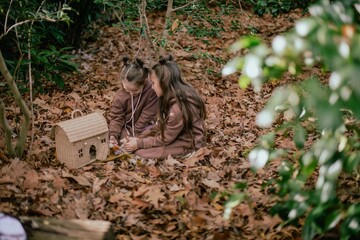 girls play in the forest with a small house