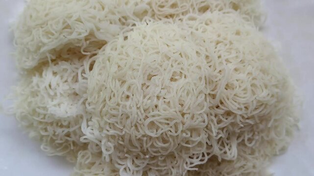 Steamed rice Idiyappam, indiappa, noolputtu, noolappam, santhagai, or ottu shavige popular traditional vegetarian dish for breakfast in south Indian states isolated and stacked on a plate or bowl.