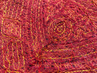 geometric thread-embroidered border in vibrant threads, accented with mirror work, elegantly placed on rich blue fabric. 