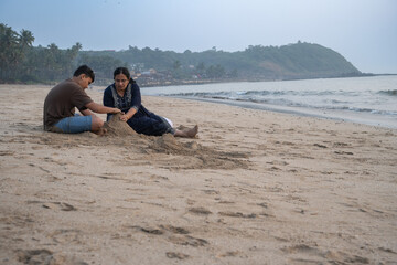 teen aged boy making sand castle at the beach with his grand mother