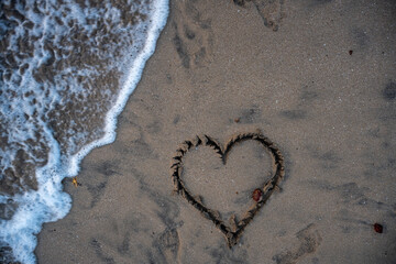 A heart is drawn on the sand on the beach at sunset. Romantic sunset on the beach. Heart shape. Heart symbol. Love.