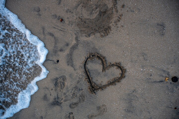 A heart is drawn on the sand on the beach at sunset. Romantic sunset on the beach. Heart shape. Heart symbol. Love.