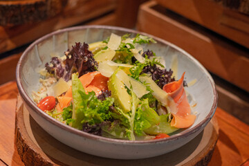Rocket salad, include smoked salmon, avocado, lettuce, tomato and italian sauce on bowl, place on wooden serving board