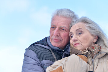 Portrait of an elderly couple hugging against the sky