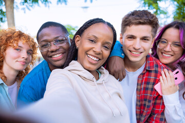 Diverse group of friends waving and smiling outdoors in a cheerful selfie