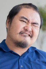 Angry Asian middle aged man with irritating expression, upset unhappy middle-age old real man biting lips with frustrated mood, serious and upset emotion