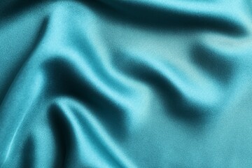 Silk satin dark turquoise color. Shiny smooth fabric. Soft folds. Luxury background with space for design. Flat table, top view