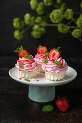 Słodka beza Pavlowa z truskawkami i kremem truskawkowym na ciemnym tle. © Dorota