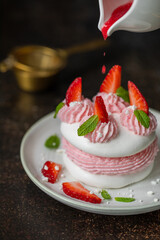 Słodka beza Pavlowa z truskawkami i kremem truskawkowym na ciemnym tle. © Dorota