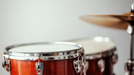 Obraz premium Close-up view of a polished drum set with a focus on the shiny tom-tom and cymbal in a minimalistic setting.