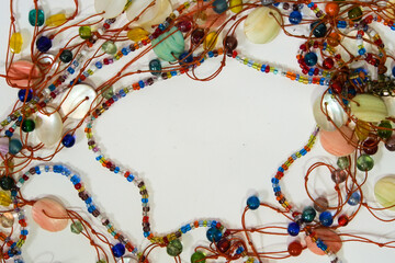 Close-up view of multicolored African beadwork of different shapes and sizes on a white background.