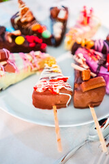 Colorful Chocolate Cake Popsicles on a White Plate with Decorative Toppings in Vibrant Colors, Ideal for Desserts, Parties, or Festive Celebrations, Creating a Delightful and Festive Atmosphere