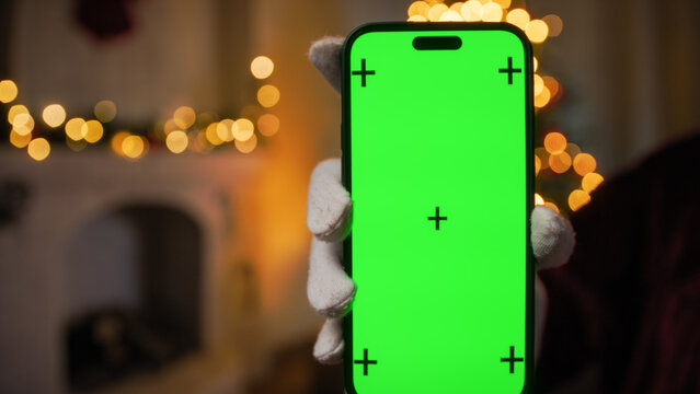 Santa Claus hand Holding a smartphone with green screen.
