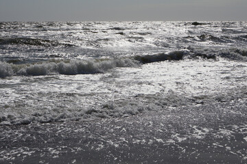 Sparkling Ocean Waves Under Sunlight. A mesmerizing ocean view with glistening waves reflecting sunlight, capturing the dynamic beauty of the sea on a bright day.