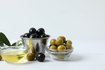 Bowl of fresh olive oil and olives with leaves on wooden background