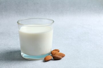 Glass of almond milk on gray background